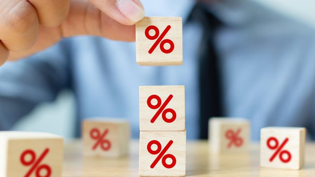 Interest rate financial and mortgage rates concept. Hand putting wood cube block increasing on top with icon percentage symbol upward direction 